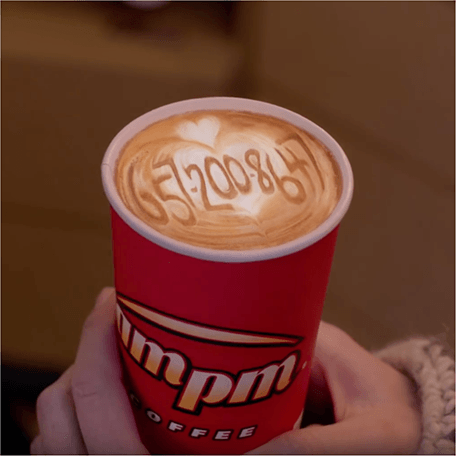 Image of a m p m coffee cup with a phone number written in froth. The number is 657-200-8647.